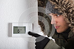 Man In Warm Clothing Pointing To Current Room Temperature