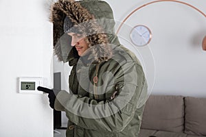 Man In Warm Clothing Pointing To Current Room Temperature