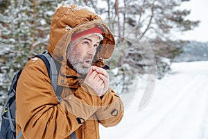 Man in warm jacket getting cold in a winter forest