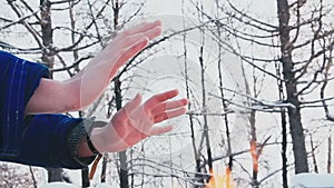 A man warms himself in the winter by the fire