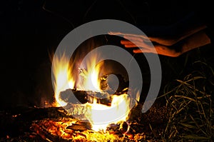 A man warms his hands at the fire.