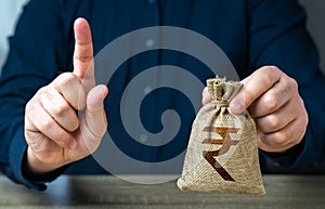 A man warns with his finger offering a indian rupee money bag.