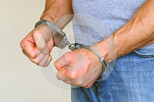 A man was detained in a police station. Handcuffs on the wrists of the detainee. Suppression of aggression