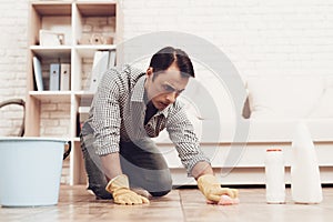 Man with Washcloth Cleaning Floor in Apartment.