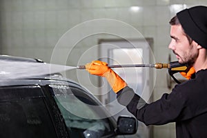 A man washes a car with a rubber hose