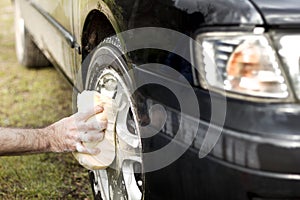 Man washes a car sponge with an aluminum alloy car shampoo