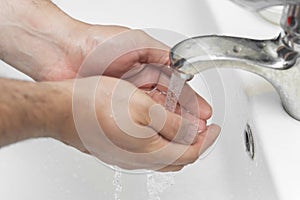 A man washes hands with soap in the bathroom. The best defense against viral infection of the crown.