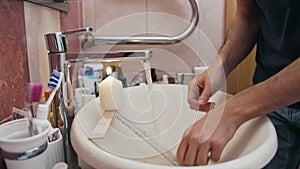 Man washes hands with water from the tap, which is heated by a lit candle