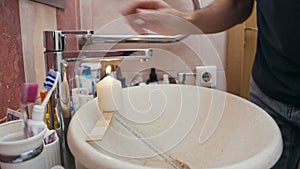 Man washes hands with water from the tap, which is heated by a lit candle