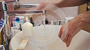 Man washes hands with water from the tap, which is heated by a lit candle