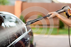 A man washes his car with a large head of water from a karcher on open air. Close up photo