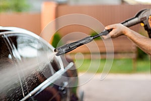 A man washes his car with a large head of water from a karcher on open air. Close up photo