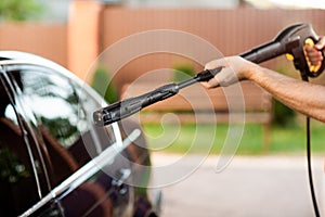 A man washes his car with a large head of water from a karcher on open air. Close up photo photo