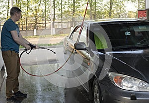 A man washes his car with pressurized water in a car wash