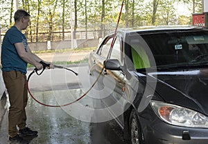 A man washes his car with pressurized water in a car wash photo