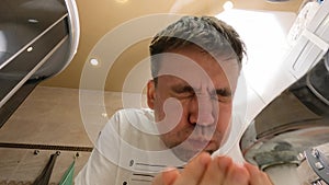 a man washes his face in the bathroom. the concept of daily hygienic procedures.