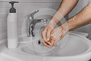 A man washes his hands with liquid soap under running water