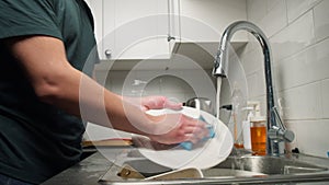 Man washes a plate in the kitchen sink.