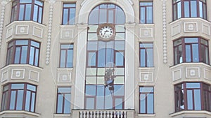 A man washes windows at height. Service cleaning the windows on the skyscraper. A window washer on a skyscraper performs