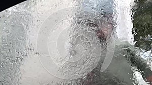 Man washes windshield of automobile with pressurised jet. Blurred glass with flowing water at manual
