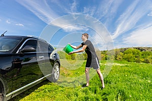 Man Washing Black Car in Green Field