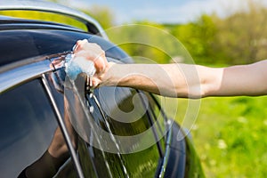 Man Washing Black Car with Soapy Sponge