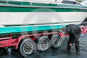 Man washing boat with pressure washer