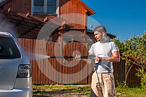 Man washing car in front of house