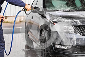 A man is washing a car at self service car wash. High pressure vehicle washer machine sprays foam. Mlada Boleslav, 10.12