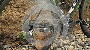 Man washing and cleaning road bicycle. Washing bike with water from hose. Washes bike chain