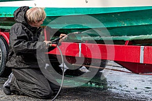 Man washing dirty boat hull with pressure washer