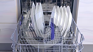 Man washing dishes loading dishwasher putting tableware and kitchenware basket.