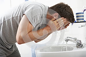 Man Washing Face In Bathroom Sink