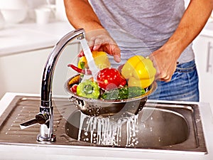 Man washing fruit at kitchen.