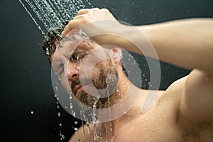 Man washing hair in bathroom. Guy bathing shower head in bathtub. Male face in shower. Man taking shower in bathroom