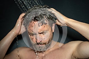 Man washing hair, close up portrait. Man bathing shower washing hair head in bathroom. Male model washing hair in shower