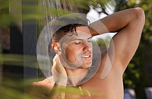 Man washing hair in outdoor shower on summer day