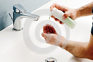 Man washing the hands in the bathroom, pushing dispenser