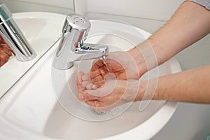 man washing hands in bathroom washbasin