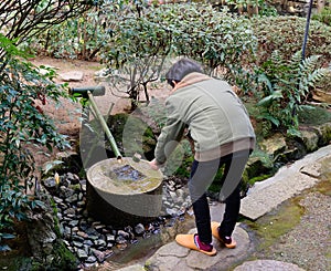 A man washing hands before coming to the temple in Tokyo, Japan