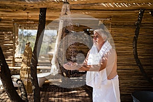 Man washing hands from shower in cottage