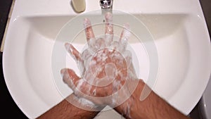Man washing hands in sink with sanitiser liquid hand wash to prevent coronavirus