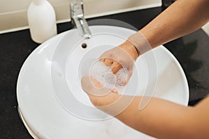 Man washing hands with soap under running water