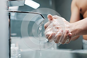 Man Washing Hands With Water And Soap In Bathroom