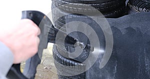 Man washing high pressure water car carpets at self service wash in cold weather. Detailing on interior of modern car