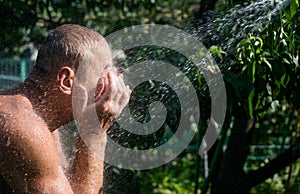 Man is washing himself under a summer shower in the garden