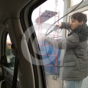 Man washing his car in a self-service car wash station. winter. Shooting from inside the car