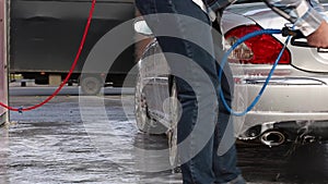 Man washing his car with water spray from high pressure washer. Car wash self-service.