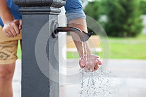 Man washing his hand in faucet water. Ð¡ity water tap with drinkable water in park.