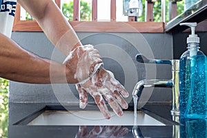 Man is washing his hands in a sink sanitizing the colona virus for sanitation and reducing the spread of COVID-19 spreading throug